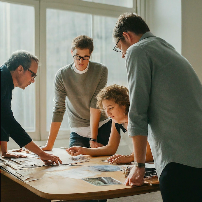 team of ad execs standing around a table looking at ad creatives